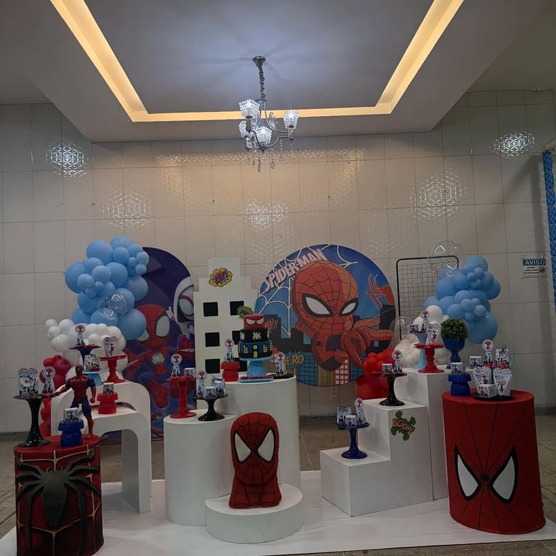 Painel do Homem-Aranha com arco de balões azul e vermelho, cubos brancos e mesa do bolo