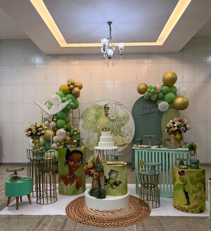 Decoração da Princesa Tiana com painel redondo, bolo de andares e balões verdes e dourados